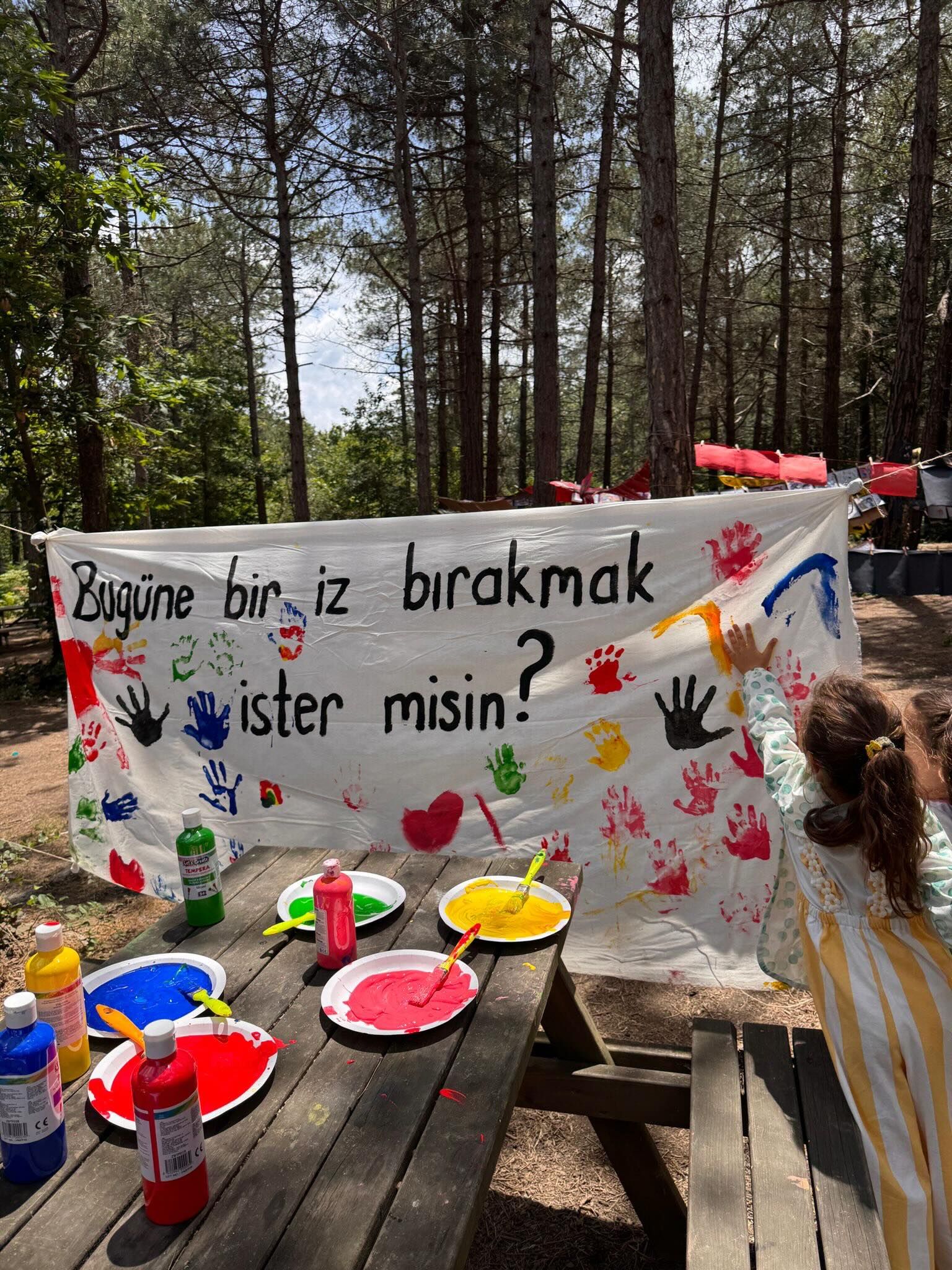 Ormanlık alanda ortak bir yüzeye el izleriyle resim yapan çocuklar